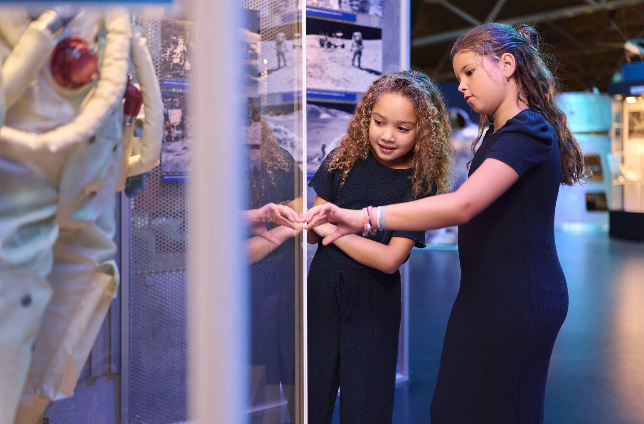 Twee meiden kijken naar een astronaut tijdens Space College bij Luchtvaartmuseum Aviodrome.