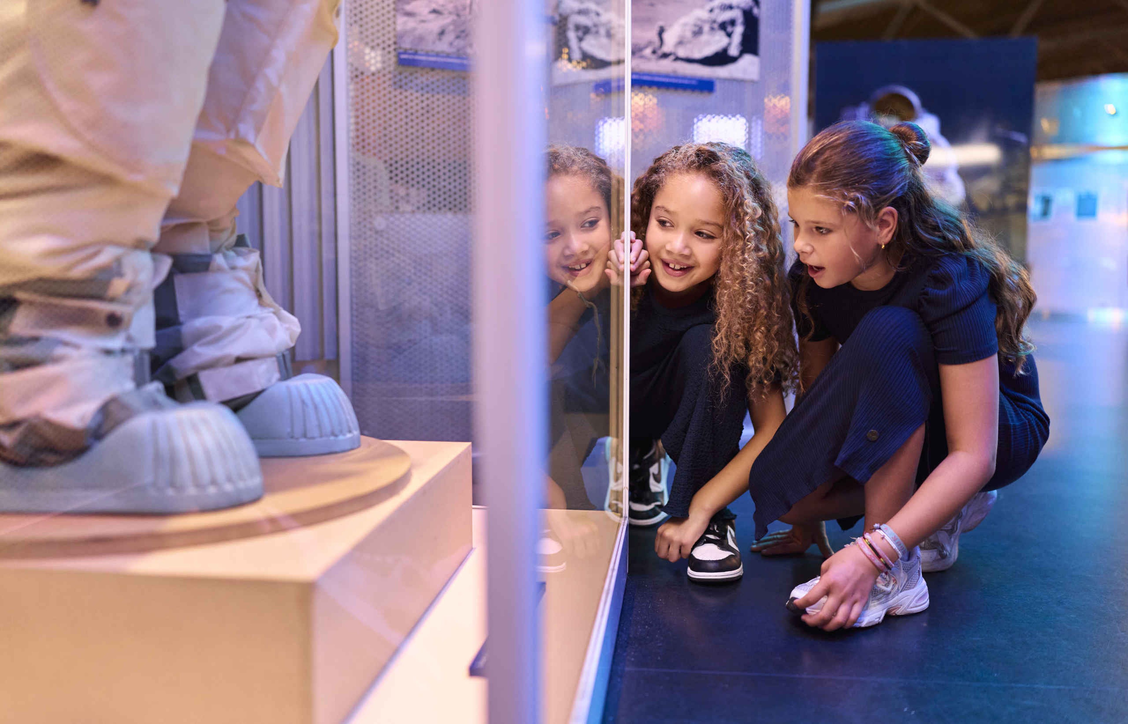 Twee meiden kijken naar een astronaut tijdens Space College bij Luchtvaartmuseum Aviodrome.