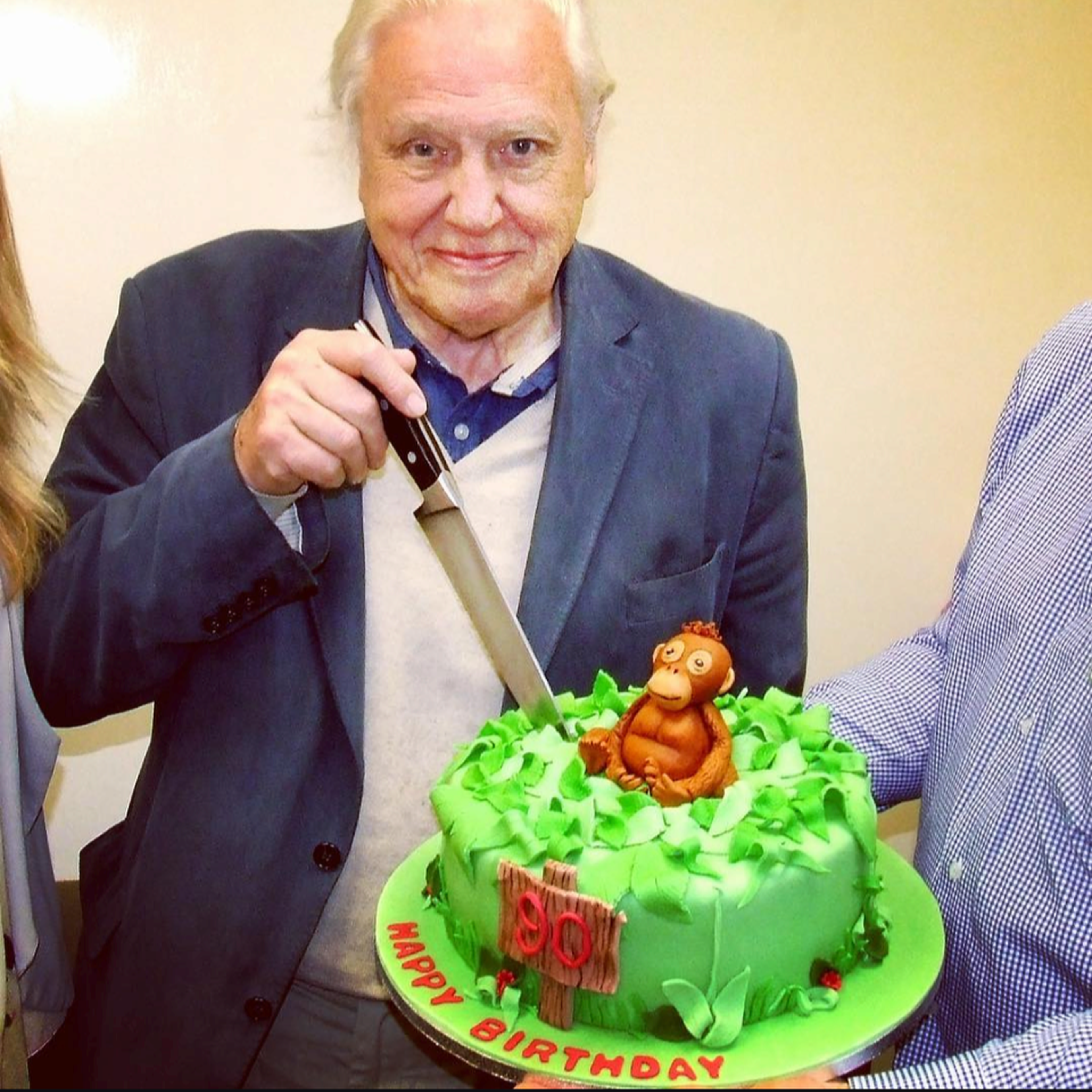 David Attenborough cutting into a cake made for him by staff member Julie Gibson at Paignton Zoo